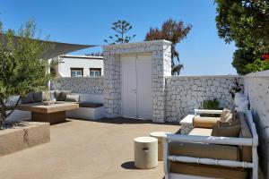 un patio con puerta blanca y pared de piedra en Olia Villa, en Imerovigli