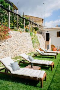 a group of chaise lounges on the grass next to a stone wall at Villa Le Murelle in Tramonti
