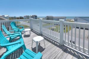 a deck with blue chairs and tables and the ocean at 1 More Day in Oak Island