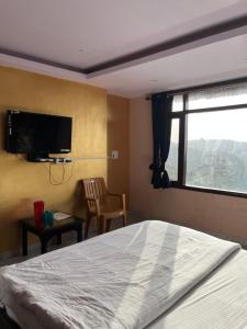 a bedroom with a bed and a flat screen tv at Vanu Homestay in Shimla