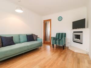 a living room with a green couch and a chair at Tillys Cottage in Weston-super-Mare