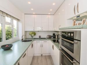 a kitchen with white cabinets and green counter tops at Tillys Cottage in Weston-super-Mare