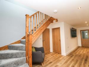 a living room with a staircase and a chair at Bramblewood Cottage in Middleton in Teesdale