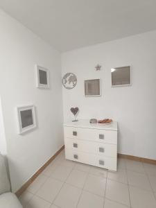 a white dresser in a white room with pictures on the wall at Sky in Noja