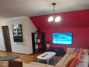 sala de estar con sofá y TV en una pared roja en Rhs Host, en Bistriţa