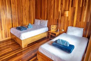 two beds in a room with wooden walls and wood floors at Cowboy Hostel - Habitaciones con Baño Privado in Monteverde Costa Rica