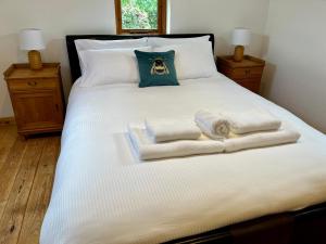 a white bed with towels on it with two lamps at The Annexe at Yew Tree House in Canterbury