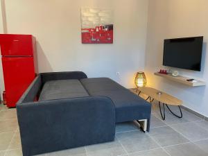 sala de estar con sofá azul y TV en Avli Luxury Apartment, en Ierissos