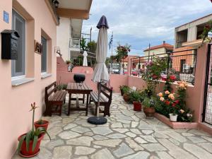 a patio with a table and an umbrella and plants at Avli Luxury Apartment in Ierissos