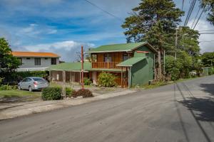 una casa con un tetto verde sul lato di una strada di Cowboy Hostel - Habitaciones con Baño Privado a Monteverde Costa Rica