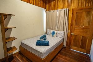 a small bed in a small room with a door at Cowboy Hostel - Habitaciones con Baño Privado in Monteverde Costa Rica