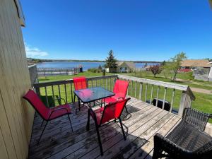 4 sillas y una mesa en una terraza con agua en Beach & Breeze Cottages, en Stanley Bridge