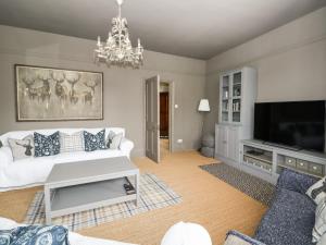 Troon Cottage في هونستنتون: غرفة معيشة مع أريكة بيضاء وتلفزيون