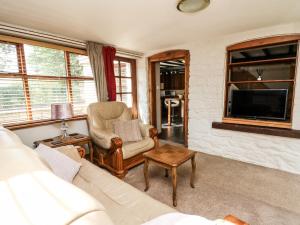 a living room with a couch and a tv at Brook Cottage in Llanidloes