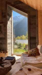 um quarto com uma grande janela com um sofá em frente em Mon Roc - Maison de montagne atypique avec vue em La Grave