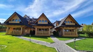 a large wooden house on top of a green lawn at Janulkowe Domki in Zakopane