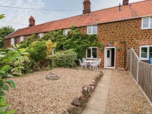 a brick house with a garden in front of it at Tawny Cottage in Heacham