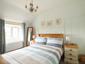 a bedroom with a bed and a chandelier at Tawny Cottage in Heacham