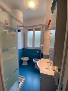 een badkamer met 2 toiletten, een wastafel en een douche bij Sun Ste in Lido di Pomposa