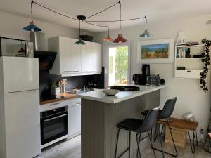 a kitchen with white cabinets and a counter with stools at Chalet Mavalear naturiste La Jenny in Le Porge