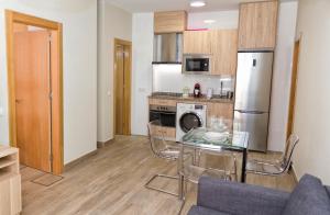 kuchnia ze szklanym stołem i lodówką w obiekcie APARTAMENTOS ONNIGHT w Maladze
