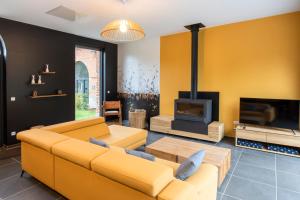 a living room with yellow furniture and a fireplace at Aux Petits Lapins de Sorval, sauna privé, fitness in Selvigny +34 photos