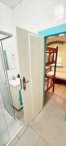 a bathroom with a door to a kitchen with a sink at Casa Viva Paraty in Paraty