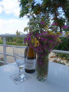 een fles wijn en een vaas met bloemen op een tafel bij Gloria Maris Cabanas Gardens in Cabanas de Tavira