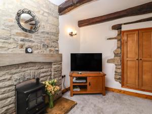 a living room with a stone fireplace and a television at 2 The Square in Skipton