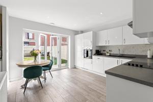 a kitchen with white cabinets and a table with a vase of flowers at Silver Stag Properties, 3 bedroom luxury house in Coalville