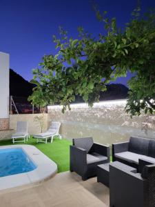 un patio trasero con piscina, sillas y mesa en Villa El Mirador, en Cortes de la Frontera
