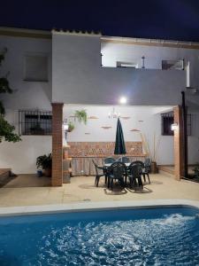 un patio con mesa, sillas y piscina en Villa El Mirador, en Cortes de la Frontera