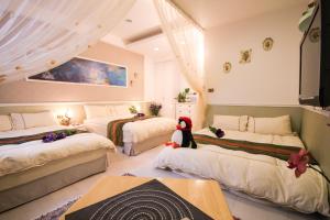 a bedroom with three beds with a stuffed animal sitting on the floor at Beautifl Sweet Warm B&B in Hualien City