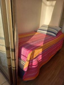 a bed with a colorful blanket on top of it at Selma Apartment in Santiago