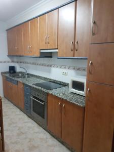 a kitchen with wooden cabinets and a stove and a microwave at Apartamento Pintor in Cambados