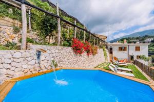 a villa with a swimming pool and a stone wall at Villa Le Murelle in Tramonti