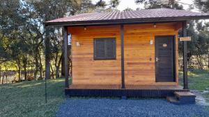 a wooden cabin with a roof on a field at Pousada Morro dos Pinhais in Urubici
