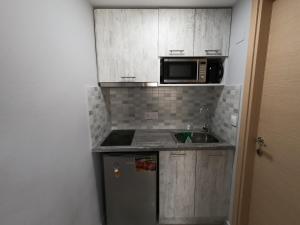 una pequeña cocina con fregadero y microondas en MEMORIA, en Corfú