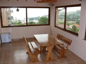 a wooden table and two chairs in a room with windows at Къща за гости Костови in Byala