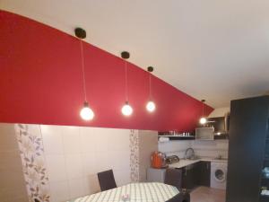 a kitchen with a red wall with lights above a table at Rhs Host in Bistriţa