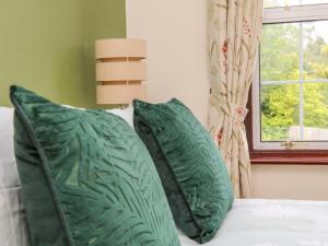 a bed with two green pillows and a window at Uptop in Dartmouth