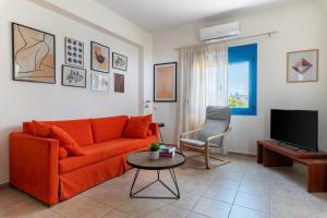 a living room with an orange couch and a tv at Sea view Pine house in Makry Gialos