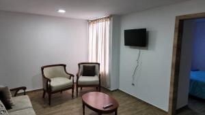 salon z 2 krzesłami, kanapą i telewizorem w obiekcie Departamento completo de dos habitaciones la Estación del Tren 3 w mieście Riobamba