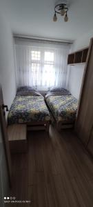 2 camas individuales en una habitación con ventana en Apartament „Nad Jeziorkiem“, en Kętrzyn