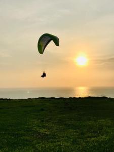 una persona volando un paracaídas sobre un campo con el océano en NEREO rooms, en Lima