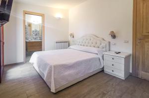 a bedroom with a white bed and a dresser and a mirror at Casa Aurora in San Pantaleo