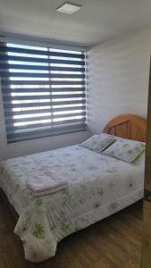 um quarto com uma cama e uma janela com persianas em Departamentos La Estación del tren de dos habitaciones em Riobamba