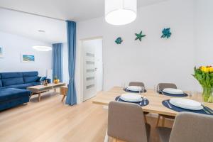 ein Wohnzimmer mit einem Esstisch und einem blauen Sofa in der Unterkunft Apartamenty Fenomen - Baltic, Nadmorskie Tarasy, FREE PARKING, SWIMMING POOL, SAUNA AND OTHER! in Kołobrzeg