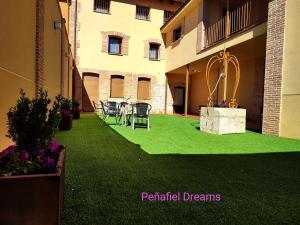 um pátio com relva verde e cadeiras num edifício em PEÑAFIEL DREAMS CON JACUZZI 4 PERSONAS em Peñafiel