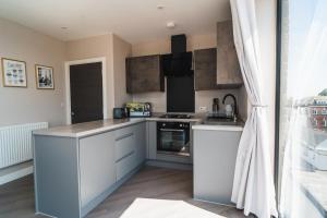 a kitchen with white cabinets and a stove at Penthouse - Harbour Views in Poole
